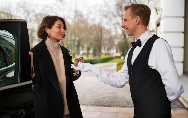 A professional RideVoova driver greeting corporate passengers with a smile outside a business venue in London.